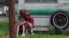 two young boys sitting on the back of an old camper