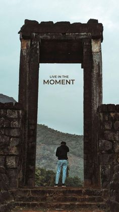 a man standing in front of an arch with the words live in the moment