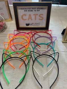 there are many different colored cat ears on the table with a sign in front of them