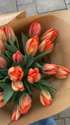 a bunch of orange tulips in a brown paper bag