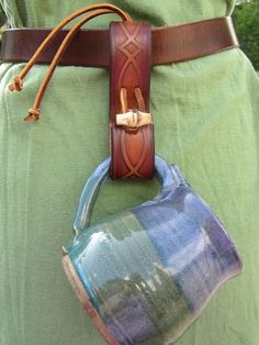 a person wearing a green shirt holding a blue and white cup in their back pocket