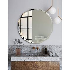 a bathroom with marble counter tops and a round mirror on the wall, along with two hanging lights