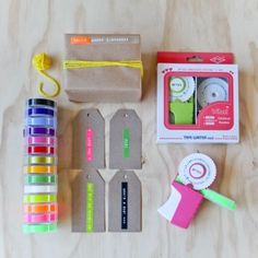 the contents of a craft kit laid out on top of a wooden table with scissors, tape and tags