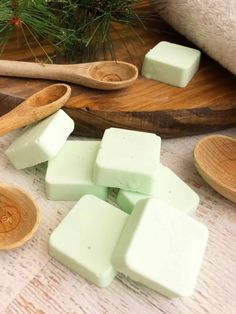 several pieces of soap sitting on top of a table next to wooden spoons and pine needles