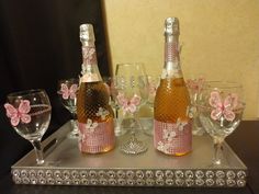 there are many wine glasses and bottles on the tray with pink butterflies in them,