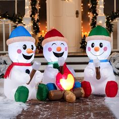 three inflatable snowmen sitting on the front porch with a fire lite