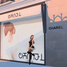 a woman standing in front of a chanel store window with her legs spread out