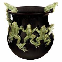 four green frog figurines sitting on top of a black vase