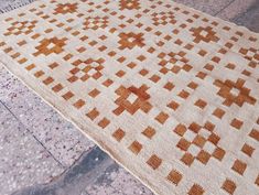 an orange and white rug on the ground with tile flooring in front of it