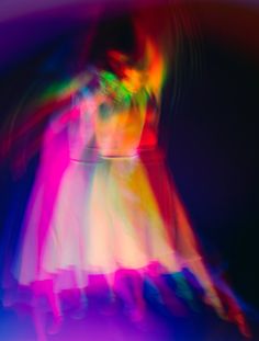 a blurry image of a woman dancing in a dress with her arms outstretched and legs spread out