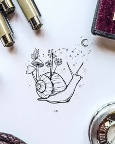 a drawing of a snail on top of a paper next to some pens and other items