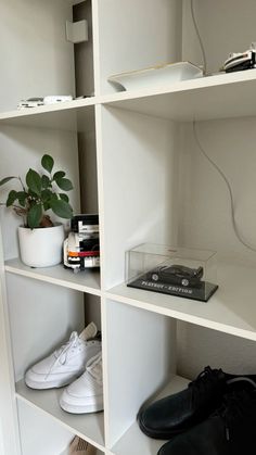 there are many shelves with shoes and other items on them in the room that is white