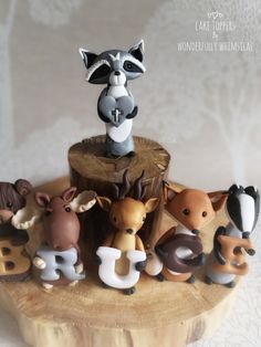 a cake topper with animals on it sitting on a tree stump in front of a white wall