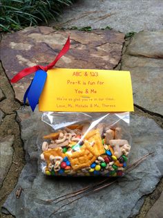 a bag filled with cereal and pretzels on top of a stone slab next to a blue ribbon