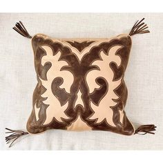 a brown and white pillow with tassels on it