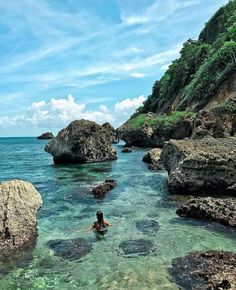 a person swimming in the ocean near some rocks