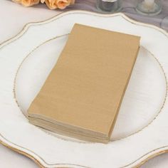 a white plate topped with a brown book on top of a table next to flowers