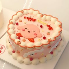 there is a pink cake with white frosting and decorations on the top, sitting on a table