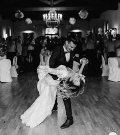 a bride and groom dance together on the dance floor at their wedding reception in black and white