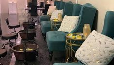 a row of blue couches with white pillows on them in a room filled with chairs and tables