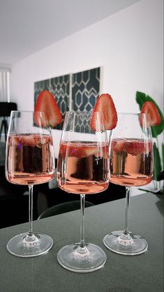 three wine glasses filled with liquid and strawberries