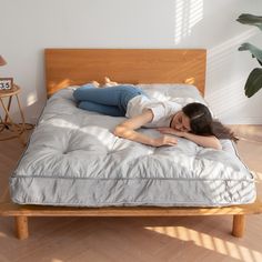 a woman laying on top of a bed next to a wooden headboard and foot board