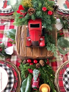 a christmas table setting with red truck and pine cones