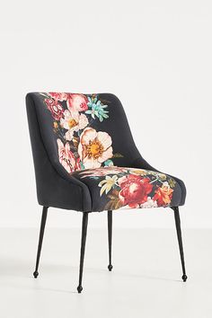 an upholstered chair with flowers on the back and black legs, against a white background