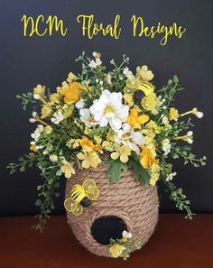 a basket filled with yellow and white flowers on top of a wooden table next to a black wall