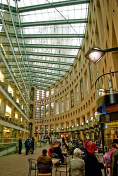 people are sitting at tables in the middle of an indoor shopping mall with high ceilings