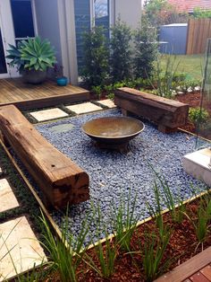 a wooden bench sitting on top of a gravel covered ground next to a garden area