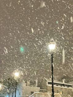 the snow is falling down on the street lights