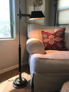 a living room with a white couch and a lamp on the floor next to it