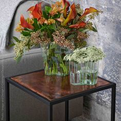 two vases filled with flowers sitting on top of a table next to a couch