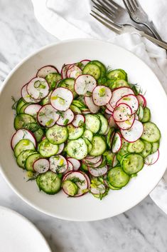 a bowl filled with cucumbers and radishes on top of a table