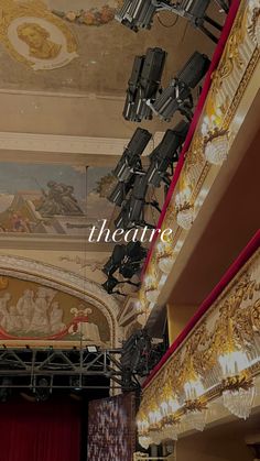 an auditorium with red curtains and chandeliers hanging from the ceiling that reads theatre