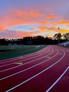 the sun is setting over a running track