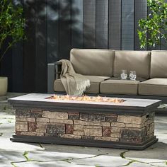 an outdoor fire pit sitting on top of a stone patio floor next to a couch