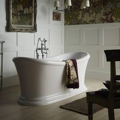 a white bath tub sitting in a bathroom next to a wooden table and chair on top of a hard wood floor