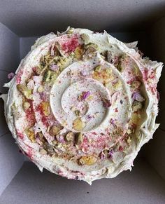 a cake in a box with white frosting and sprinkles