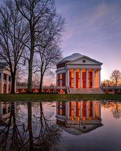 the building is reflecting in the water at sunset