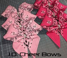 three bows are laying on a cutting board, one is pink and the other is red