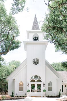 a white church with a bell tower in the middle of it's front yard