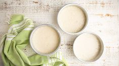 three bowls filled with batter sitting on top of a green and white towel next to each other