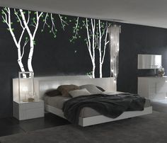 a bed room with a neatly made bed and trees on the wall