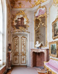 an ornately decorated room with gold and pink decor on the walls, fireplace and mirror