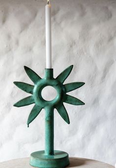 a green candle holder sitting on top of a wooden table next to a white wall