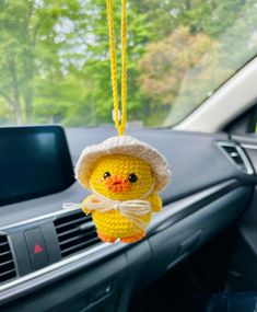 a stuffed duck hanging from the dashboard of a car with a knitted hat on it's head