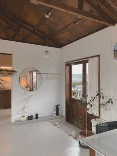 a white room with a wooden ceiling and large mirror hanging from the wall above it