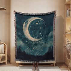 a woman standing in front of a large tapestry with the moon and stars on it